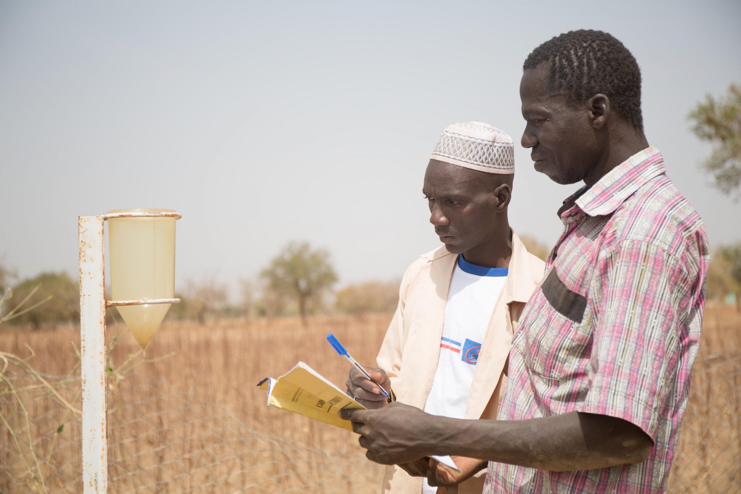 Moustapha (back) and his colleague Desire (front) recording from a rain gauge. They volunteer as water monitors in the village of Sablogo, province of Koulpelogo, Burkina Faso.
