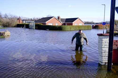 A man walks through floodwaters in the village of East Cowick after the River Aire bursts its banks on March 02, 2020 in Goole, England. There are several key areas of risk requiring urgent actions, including flooding, heat exposure and loss of biodiversity.