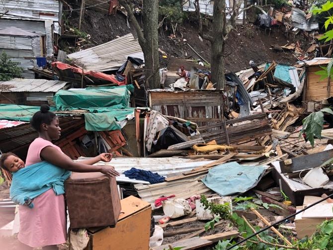 A woman with a child surveys debris hoping to salvage any household items in the aftermath of the floods.